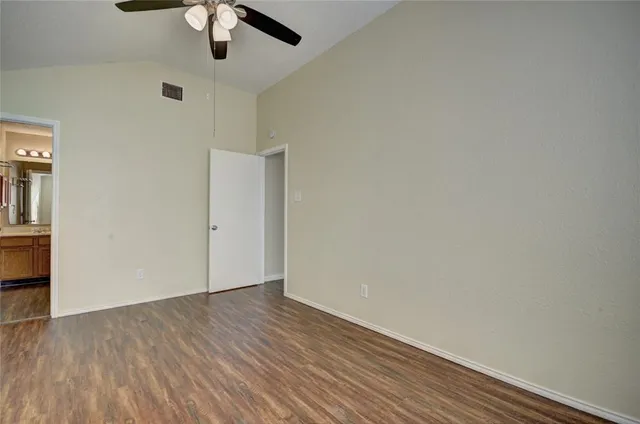 an empty room with a hardwood and ceiling fan