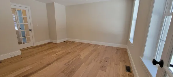 an empty room with wooden floor and entrance