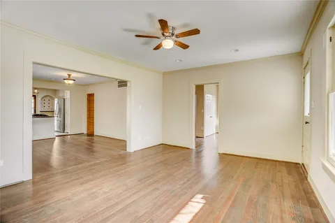 an empty room with wooden floor and a ceiling fan