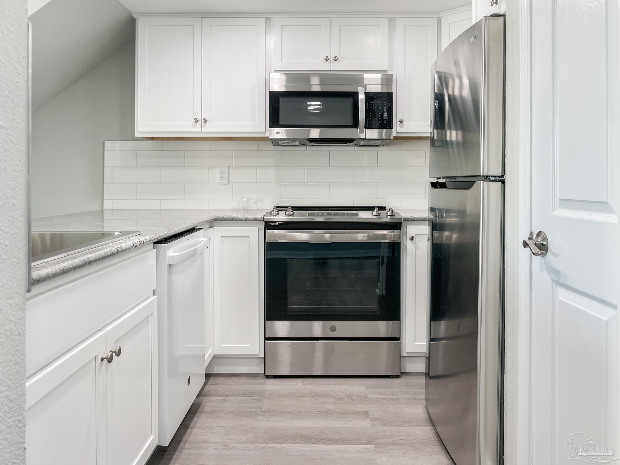 7200 Sharp Reef, Unit 2 Pensacola, FL 32507 - Photo 10 of 24 a kitchen with stainless steel appliances granite countertop a stove a microwave and a refrigerator