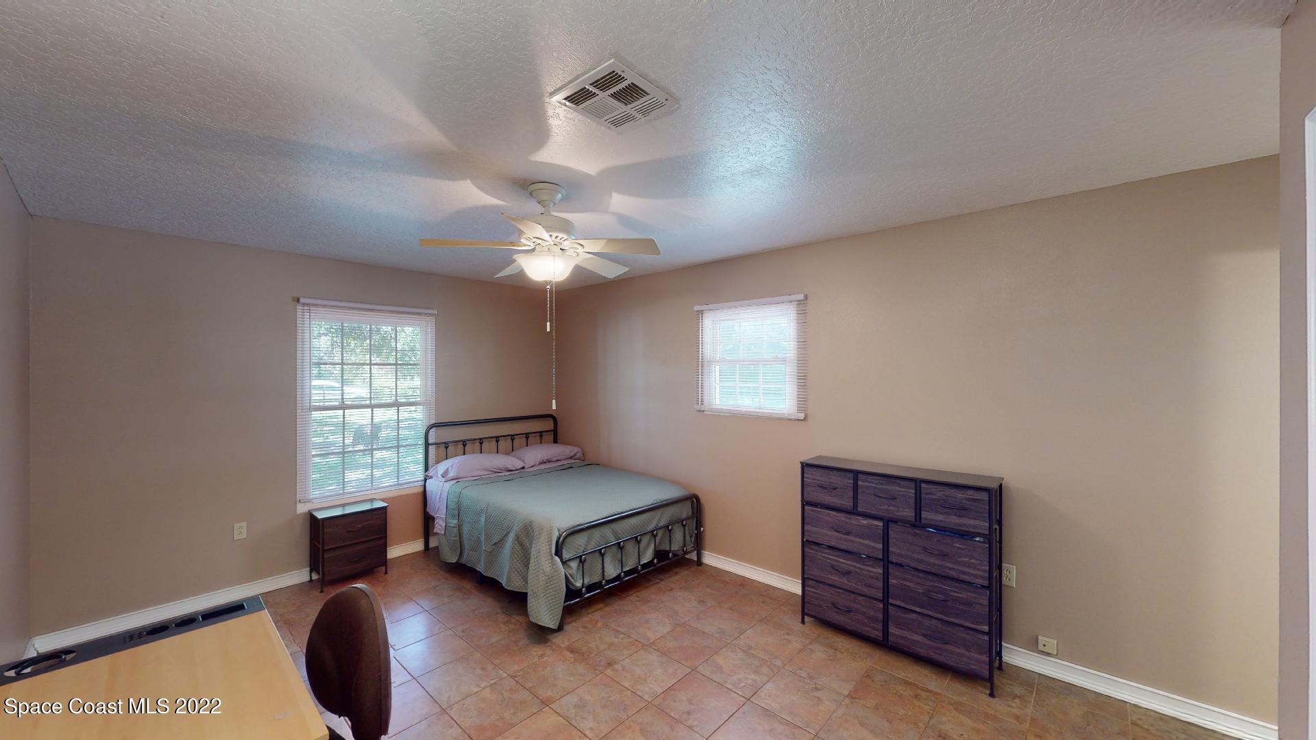 2005 Cox Road Cocoa, FL 32926 - Photo 21 of 35 a bedroom with a bed a chandelier and dresser