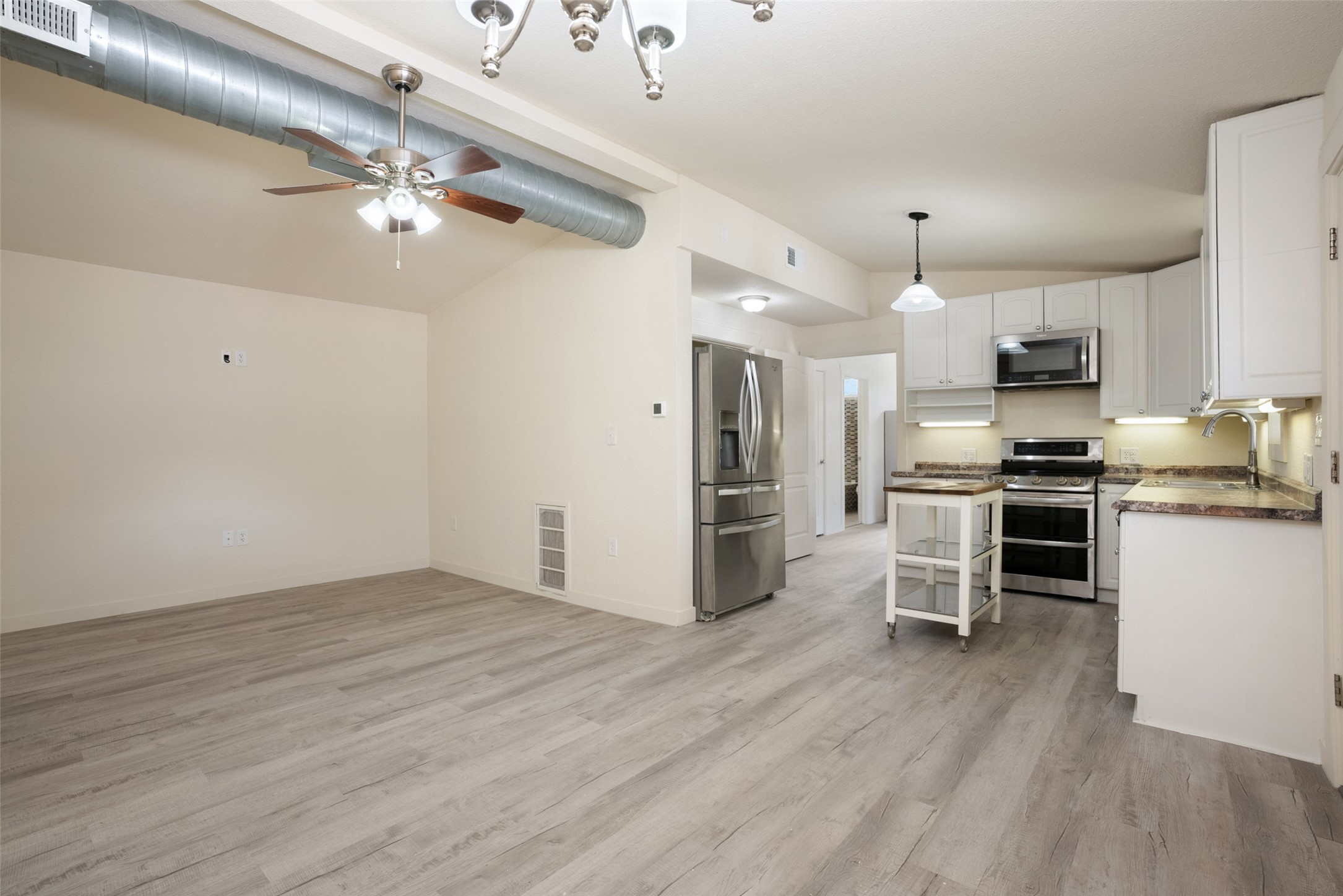 15303 Faubion Trail Leander, TX 78641 - Photo 29 of 39 a kitchen with stainless steel appliances a refrigerator oven a sink dishwasher and white cabinets with wooden floor
