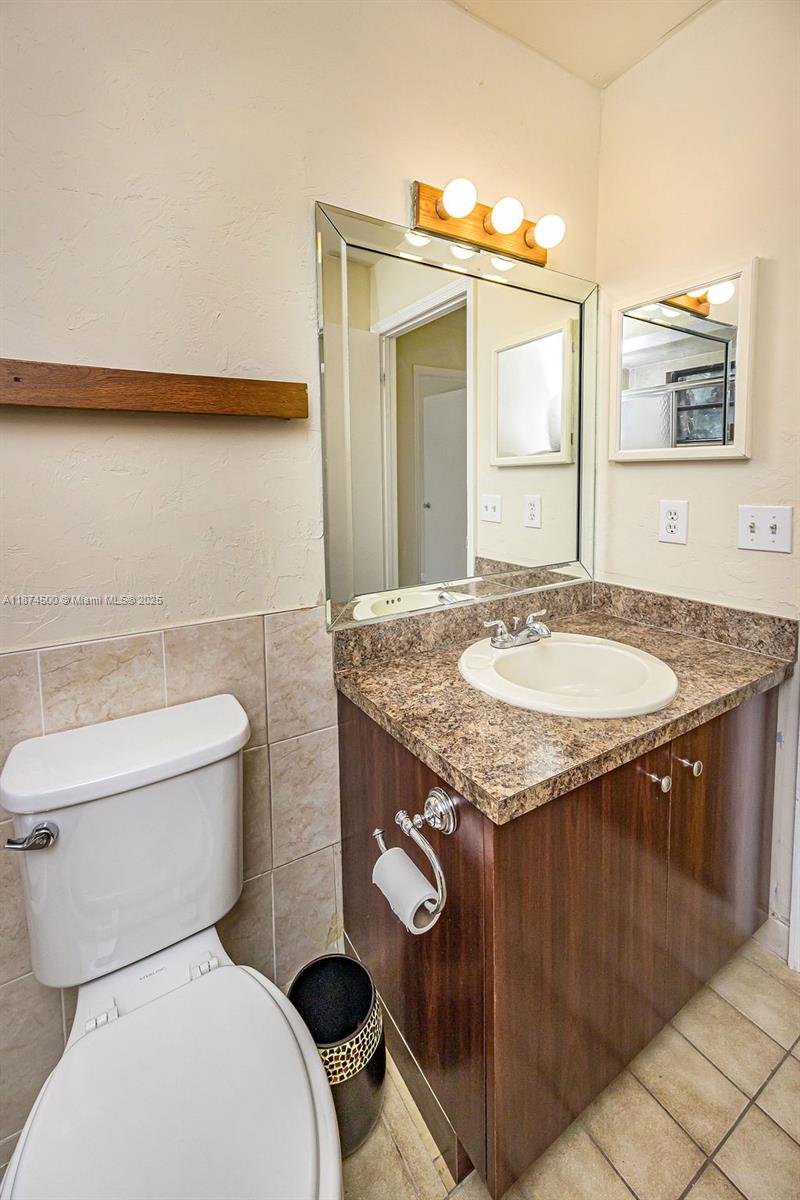 4882 Southeast Bayshore Terrace Stuart, FL 34997 - Photo 44 of 56 a bathroom with a granite countertop toilet sink and mirror