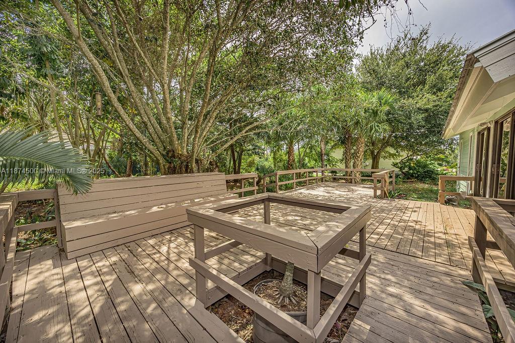 4882 Southeast Bayshore Terrace Stuart, FL 34997 - Photo 9 of 56 a view of a patio with table and chairs with wooden floor and fence