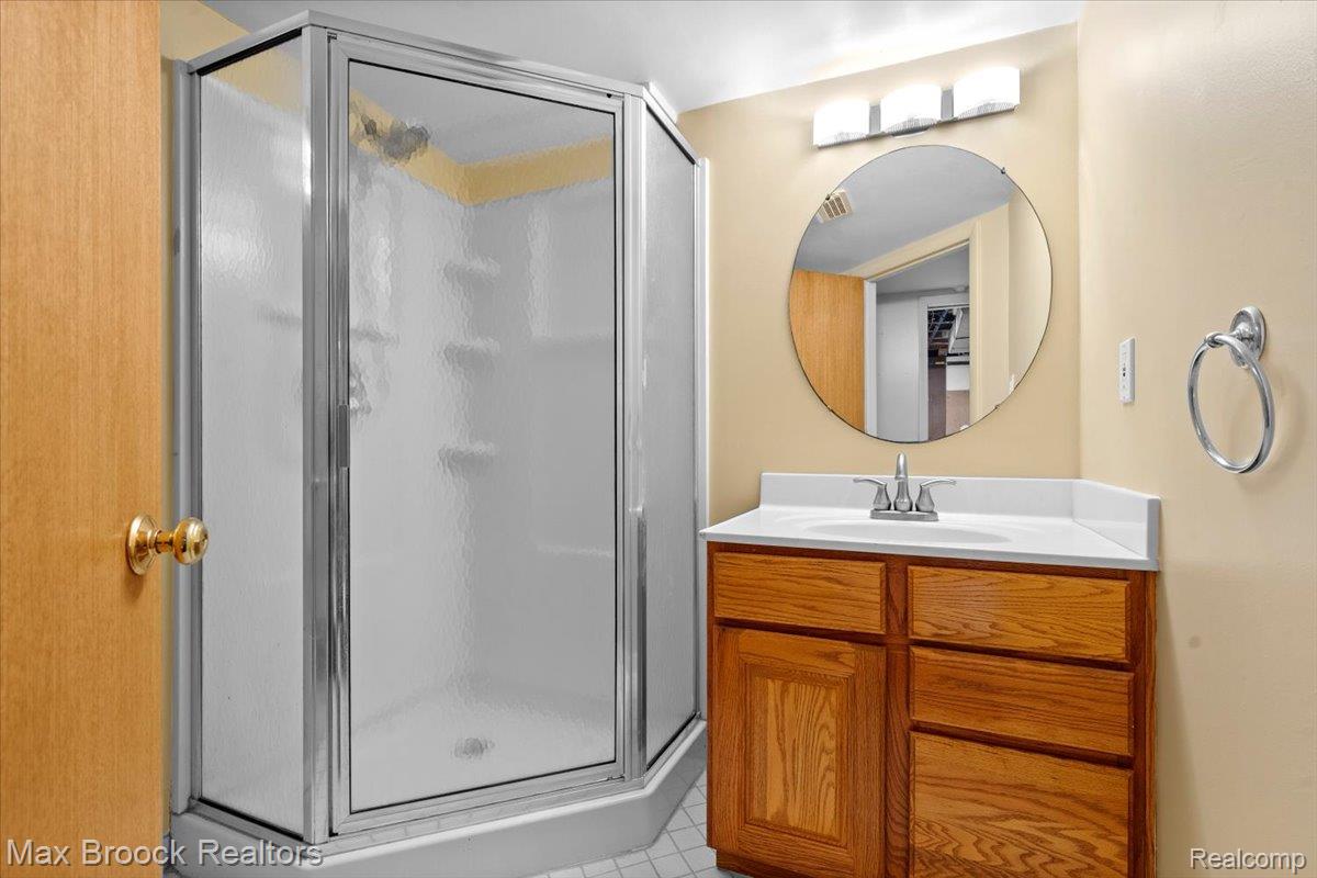 1330 Oak Street Rochester, MI 48307 - Photo 20 of 35 Corner shower with clear and frosted glass enclosure, single-basin vanity with wood-finish cabinetry, white countertop, and chrome faucet