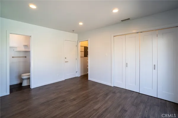 a view of an empty room with wooden floor and a toilet