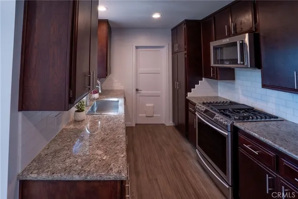 a kitchen with granite countertop wooden cabinets and stainless steel appliances