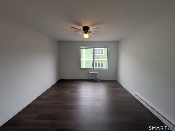 an empty room with wooden floor ceiling fan and windows