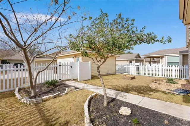 a view of a white house with a yard with wooden fence