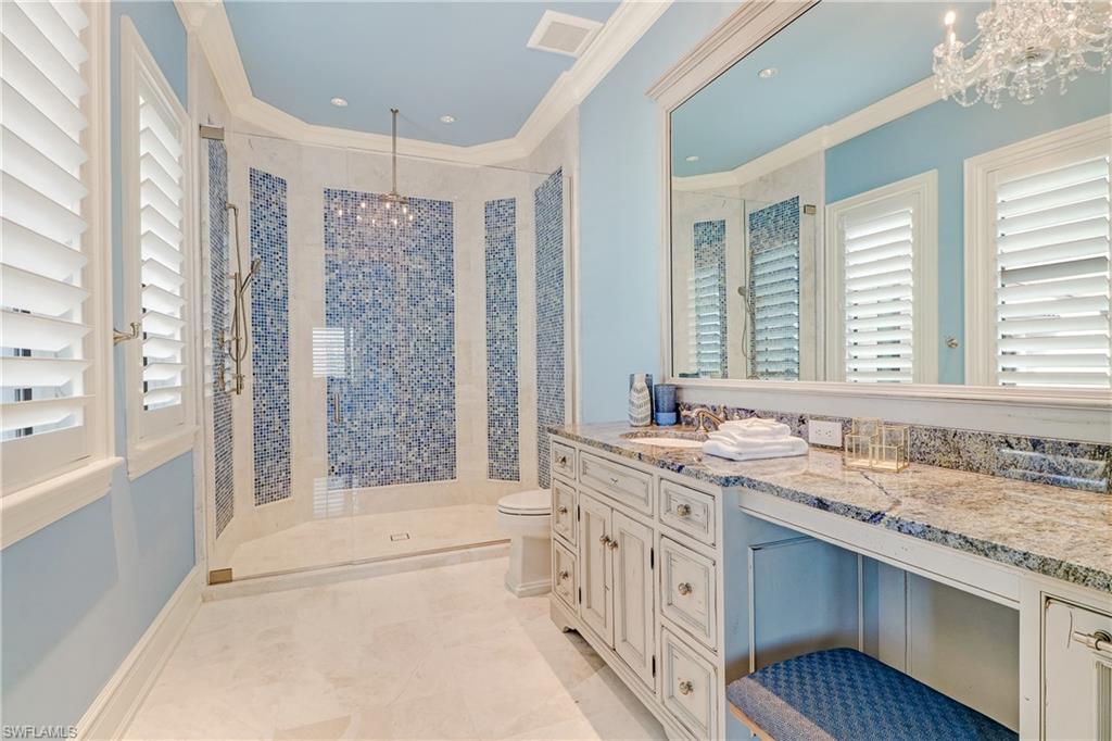 16622 Firenze Way Naples, FL 34110 - Photo 25 of 35 a bathroom with a granite countertop sink a large mirror a bathtub and next to a window