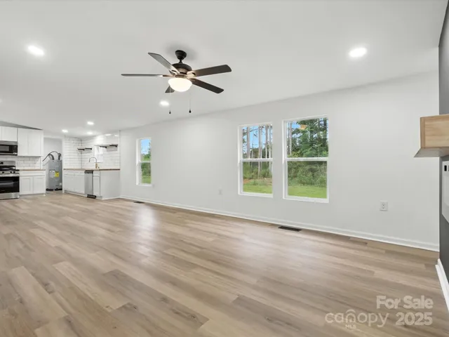 a view of an empty room with a window and wooden floor