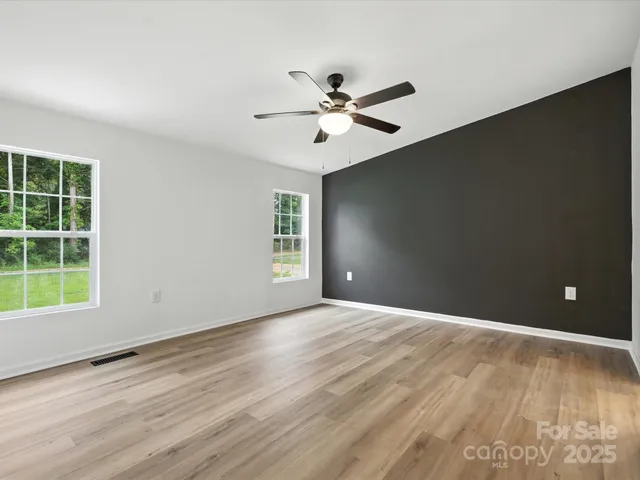 a view of an empty room with a window and wooden floor