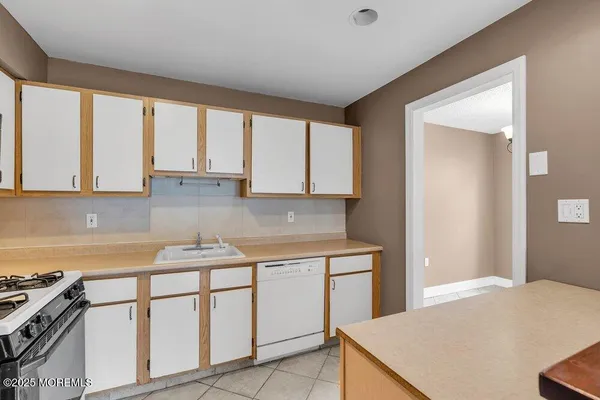 a kitchen with stainless steel appliances granite countertop a stove a sink and white cabinets