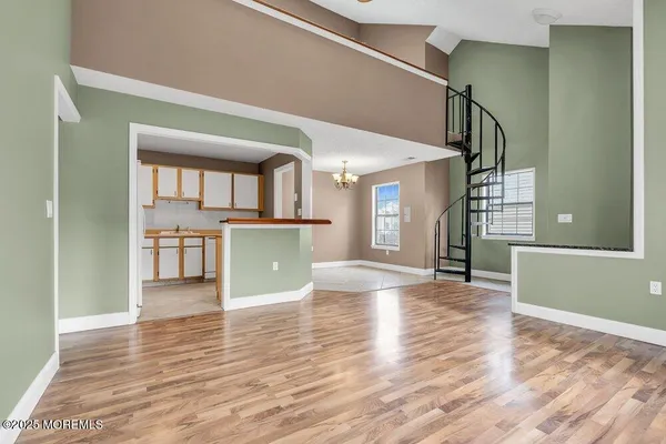 a view of a living room with wooden floor and a kitchen
