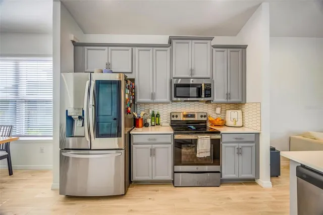 a open kitchen with stainless steel appliances wooden floor and a refrigerator