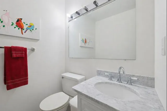 a bathroom with a granite countertop sink a mirror and a toilet