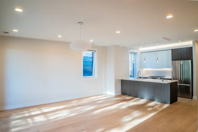 a large white kitchen with kitchen island a sink dishwasher a stove and a refrigerator with wooden floor