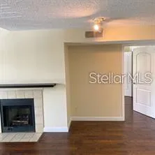 a view of an empty room with wooden floor and a fireplace