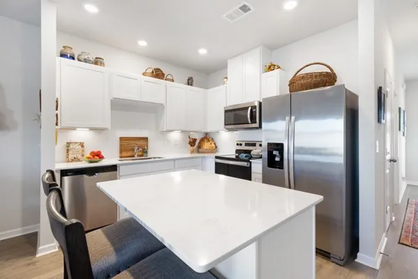 a kitchen with a refrigerator a stove a sink and chairs