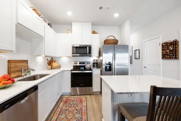 a kitchen with granite countertop a sink stainless steel appliances and cabinets