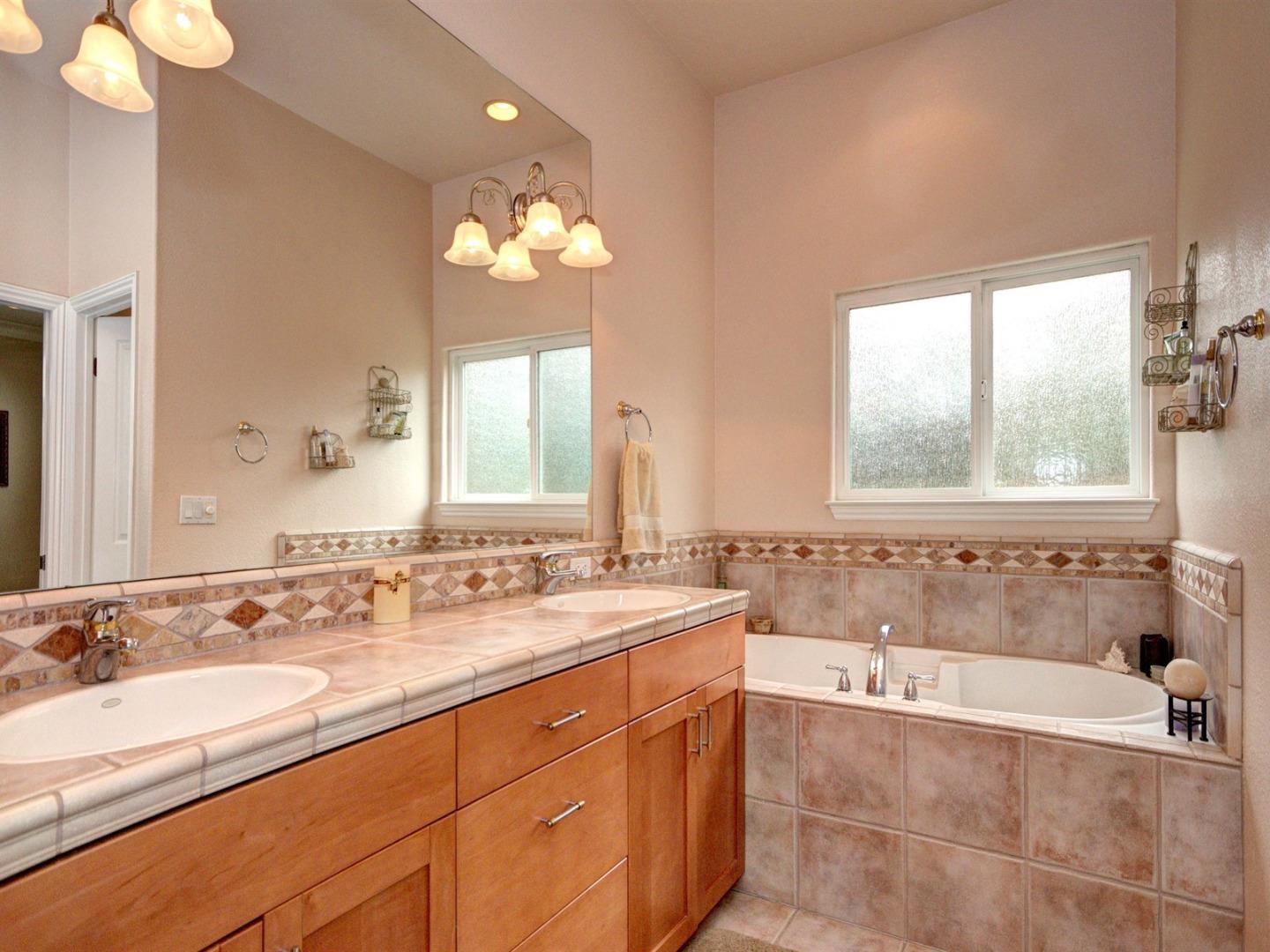10340 Moretti Drive Cupertino, CA 95014 - Photo 12 of 18 a bathroom with a tub a double vanity sink and a mirror