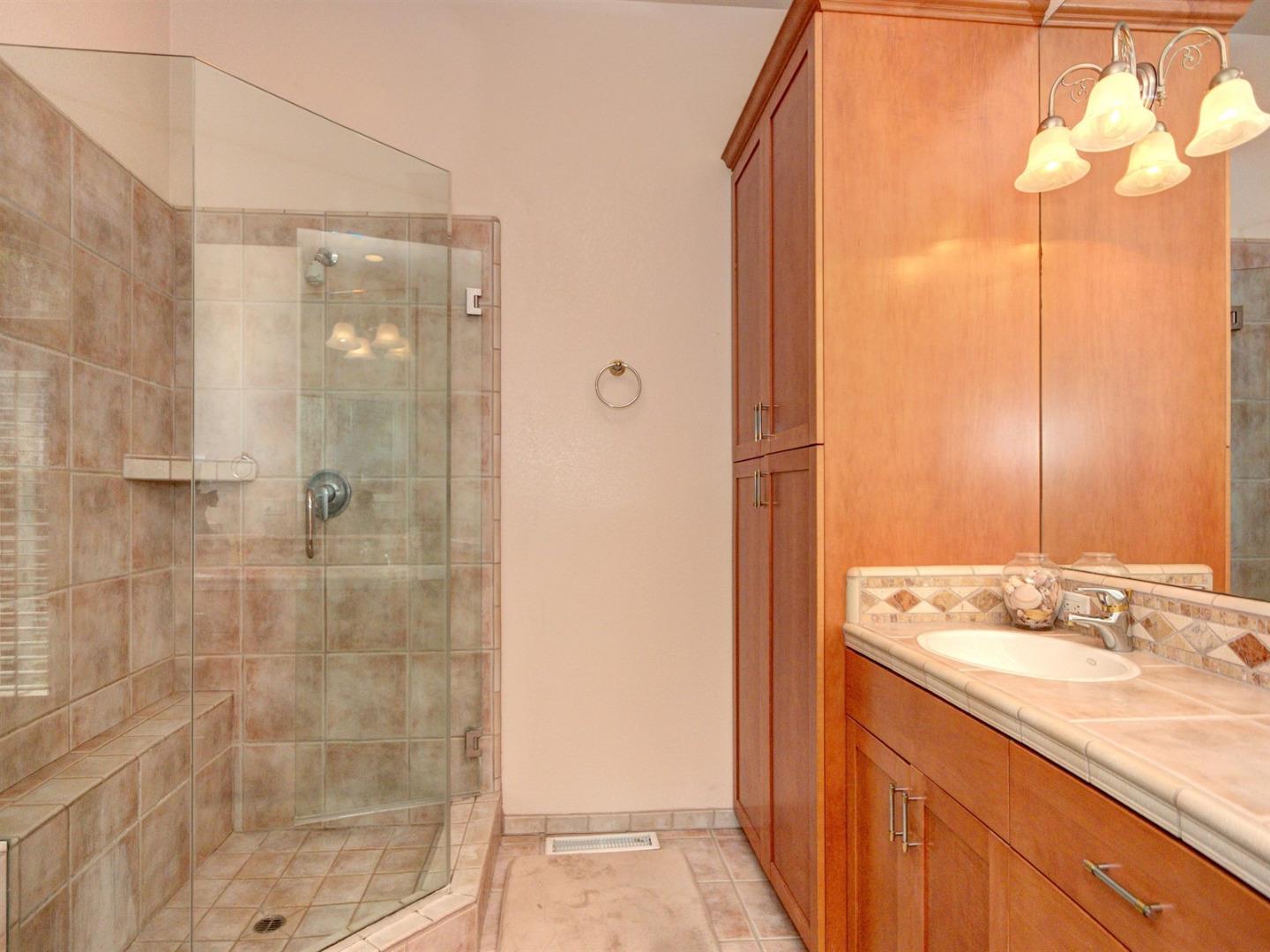 10340 Moretti Drive Cupertino, CA 95014 - Photo 13 of 18 a bathroom with a granite countertop sink a shower and a mirror