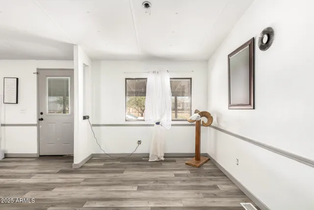 a view of empty room with wooden floor and window