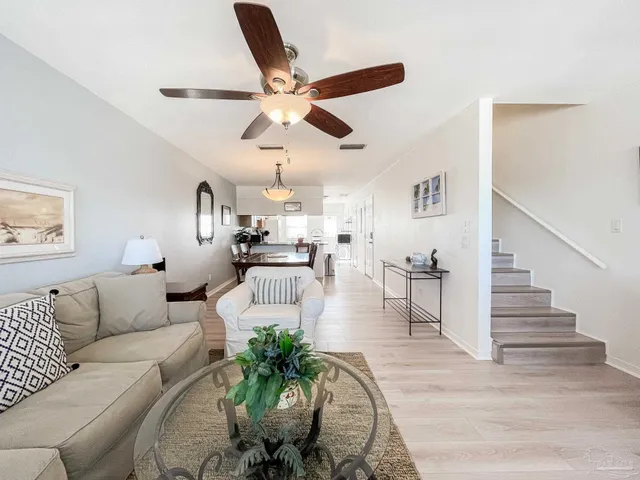 a living room with furniture kitchen view and a chandelier