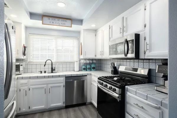 a kitchen with cabinets appliances a sink and a window
