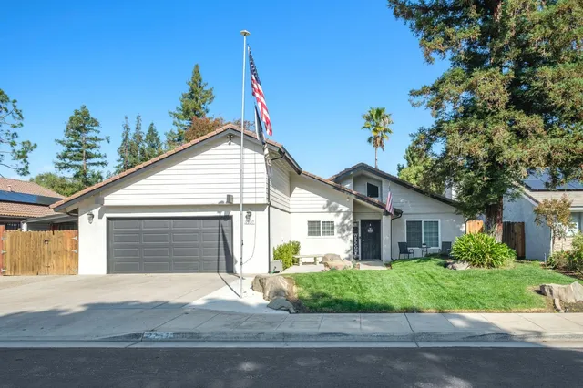 a view of a white house next to a yard with potted plants