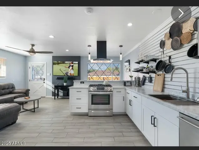 a large kitchen with stainless steel appliances kitchen island granite countertop a large stove a sink dishwasher and white cabinets with wooden floor