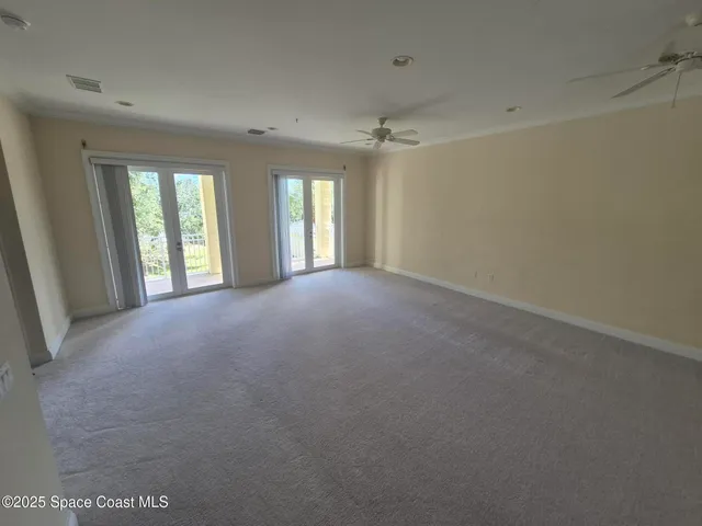 a view of a big room with windows and chandelier fan