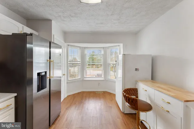 a kitchen with a refrigerator and wooden floor