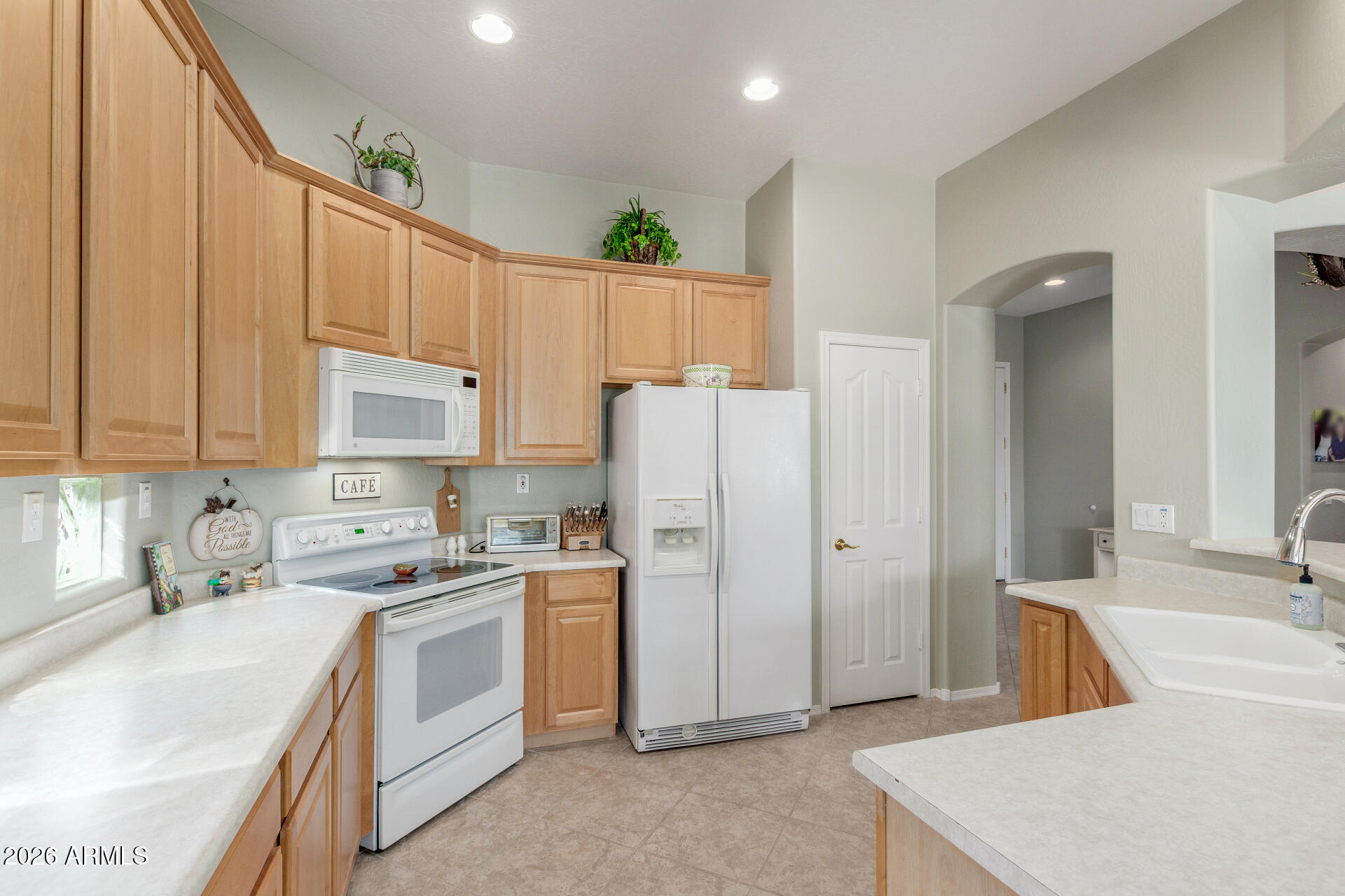 3553 East Washington Avenue Gilbert, AZ 85234 - Photo 11 of 30 a kitchen with a sink a stove a refrigerator and white cabinets