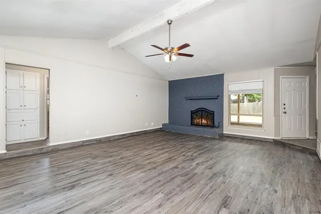 a view of empty room with wooden floor and fireplace