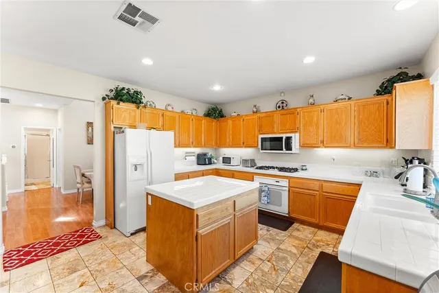 a large kitchen with stainless steel appliances granite countertop a sink and a refrigerator