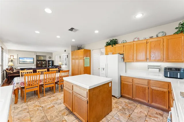 a large kitchen with a large counter top space a sink a refrigerator and wooden cabinets