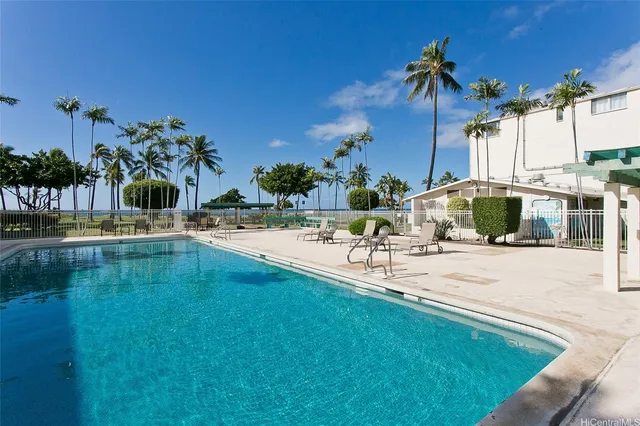 a view of a swimming pool with a lawn chairs under an umbrella