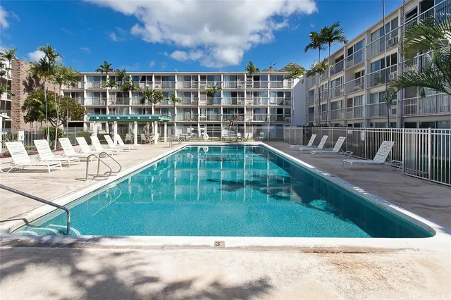 a view of a swimming pool with a lawn chairs and potted plants
