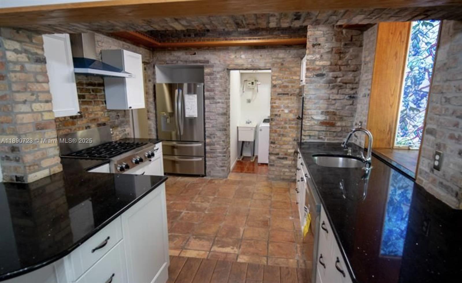 3050 Alton Road Miami Beach, FL 33140 - Photo 16 of 41 a kitchen with granite countertop a refrigerator a stove and a sink