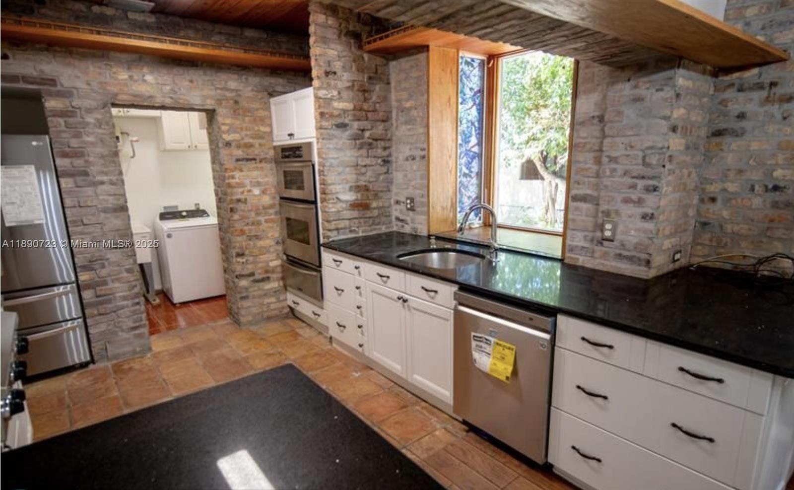 3050 Alton Road Miami Beach, FL 33140 - Photo 17 of 41 a kitchen with granite countertop a refrigerator and a sink
