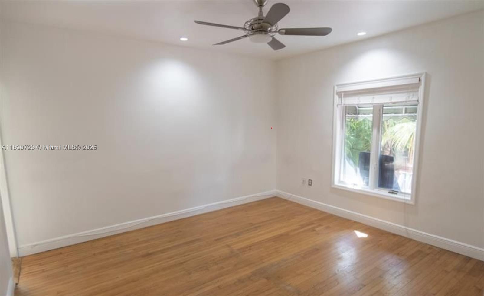 3050 Alton Road Miami Beach, FL 33140 - Photo 25 of 41 an empty room with wooden floor fan and windows