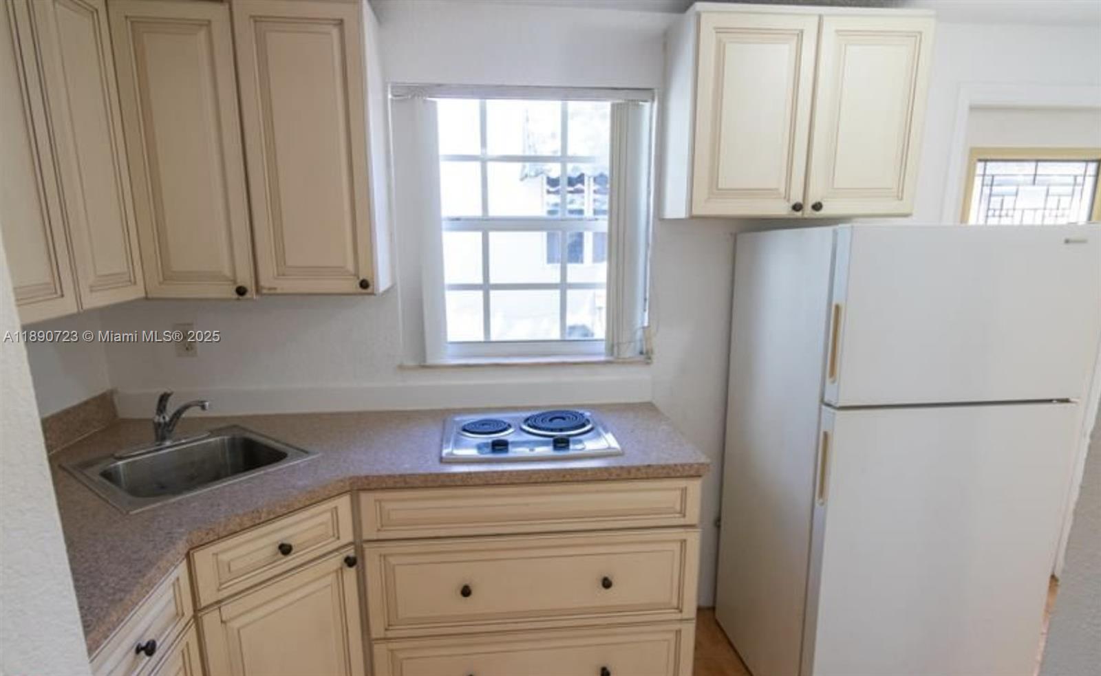 3050 Alton Road Miami Beach, FL 33140 - Photo 36 of 41 a kitchen with granite countertop white cabinets and refrigerator