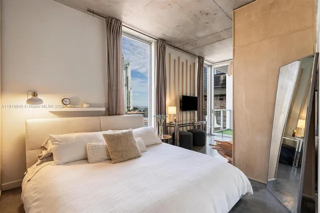 a bedroom with a large bed and a flat tv screen on dresser