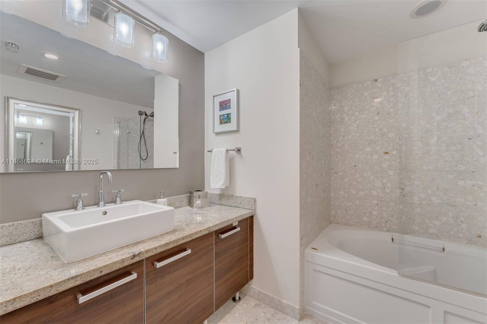 185 Southwest 7th Street, Unit 3605 Miami, FL 33130 - Photo 18 of 24 a bathroom with a granite countertop sink a mirror a bathtub and shower