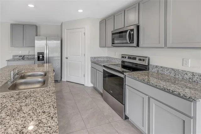 a kitchen with granite countertop a sink stove and refrigerator