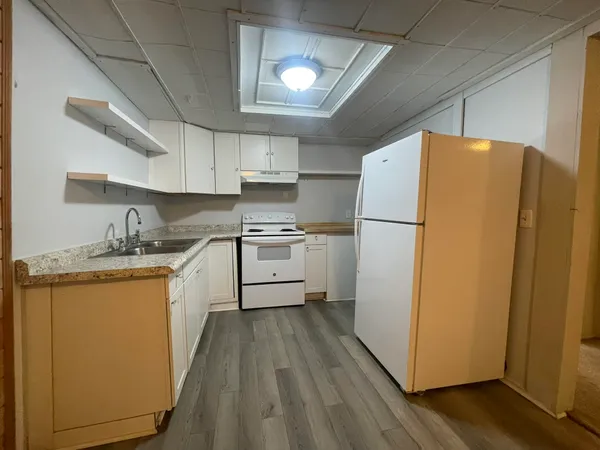 a kitchen with sink a refrigerator and white cabinets