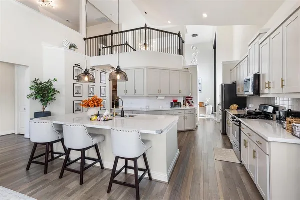 a kitchen with stainless steel appliances a sink a stove a refrigerator cabinets and a dining table