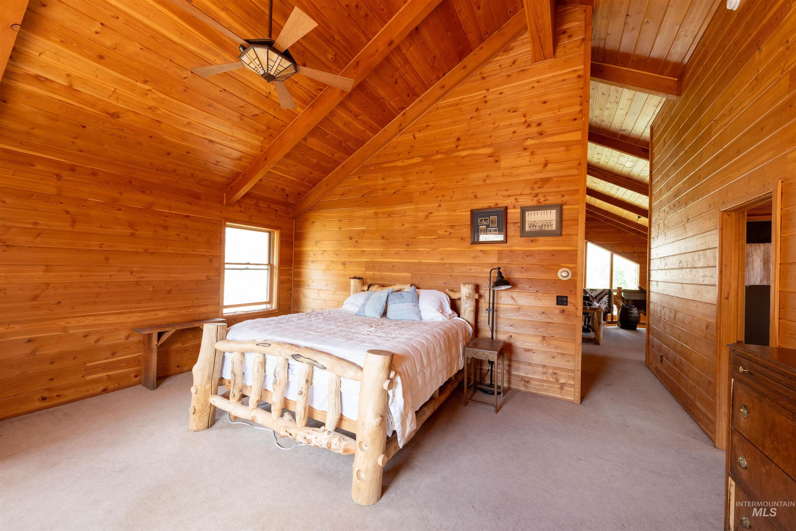 9885 Challis Creek Road Challis, ID 83226 - Photo 17 of 48 Bedroom with a ceiling fan, wooden walls, light colored carpet, a wooden ceiling with exposed beams, and high vaulted ceiling