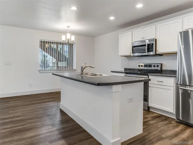 a kitchen with stainless steel appliances granite countertop a sink dishwasher a refrigerator and a stove with wooden floor